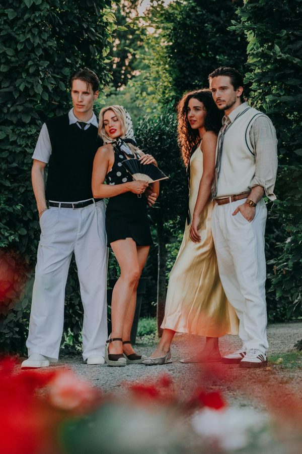 A fashionable group of adults posing in trendy summer outfits in a garden setting.