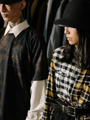 Fashion-forward man and woman wearing stylish hats and plaid shirts in a clothing store.